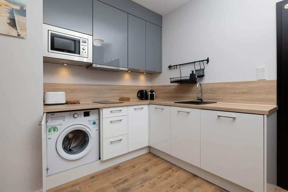 A detailed view of a functional kitchen featuring a washing machine, stove, and light wood countertops.