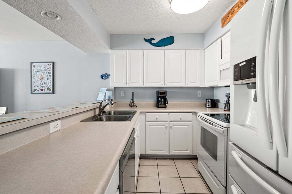 Kitchen with white cabinetry, light blue walls and a whale on the wall at Paradise Pointe 4B in Cherry Grove