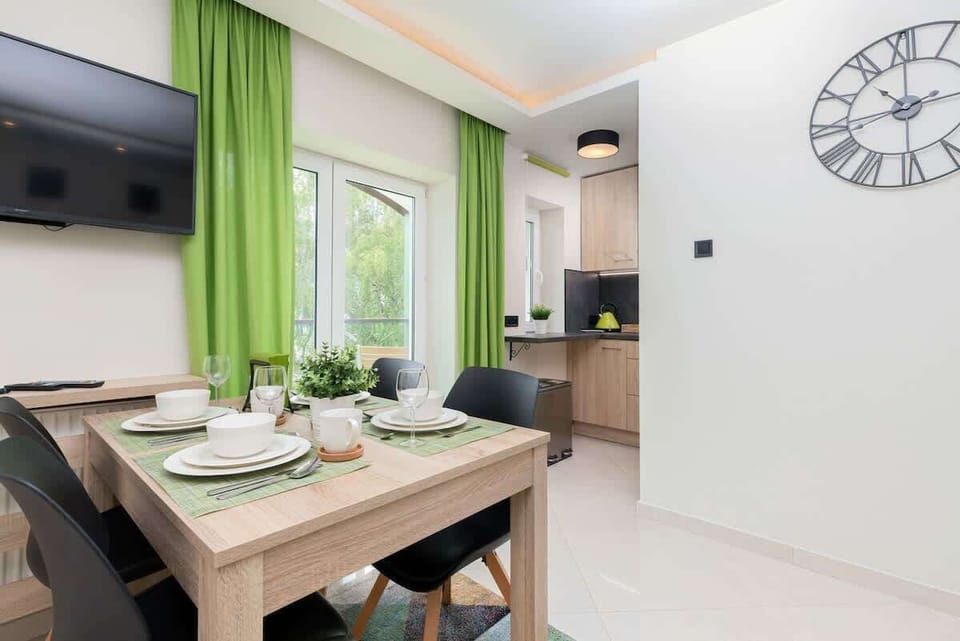 A modern kitchen with light wooden cabinetry, a black countertop, and a minimalist design.
