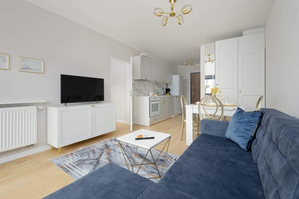 Another angle of the living room showcasing the blue sofa, the dining area, and large windows for ample natural light, ensuring a vibrant atmosphere.

