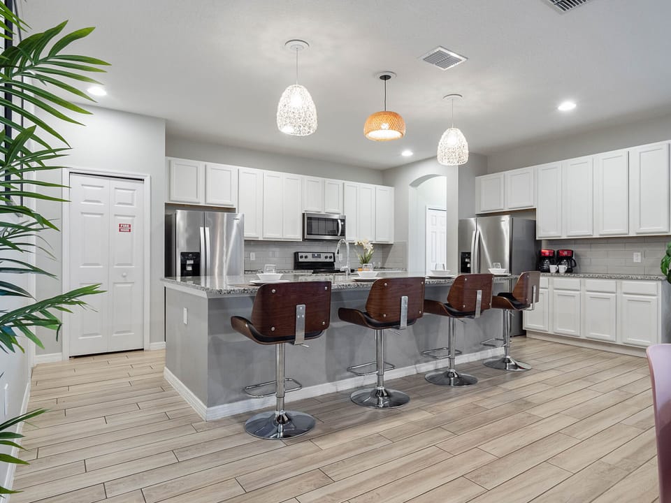 - Fully equipped kitchen with stainless steel appliances  
- Large island with bar stools and pendant lighting  
- Orlando vacation rental with modern kitchen setup