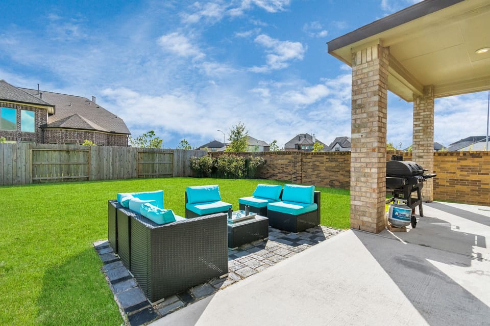 Backyard with patio seating and propane/charcoal grill.
