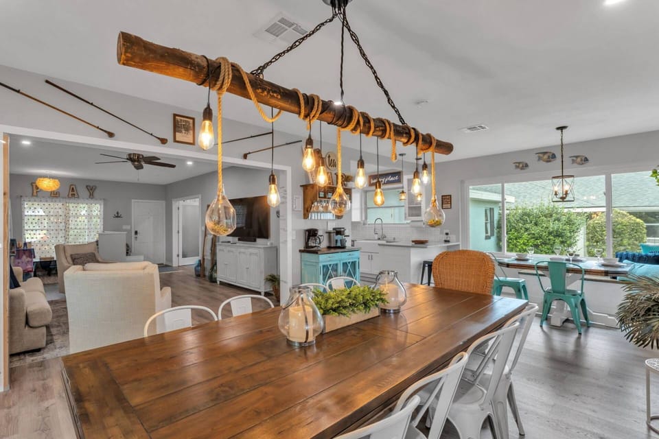 Rustic driftwood chandelier crowns a spacious dining table in this bright, open-concept living space.