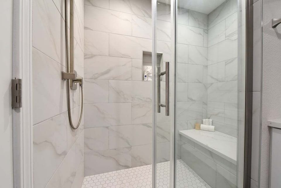 Fresh, contemporary walk‑in shower with clean white tile and glass enclosure