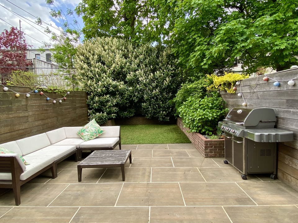Leafy backyard with comfy sofa and large gas grill