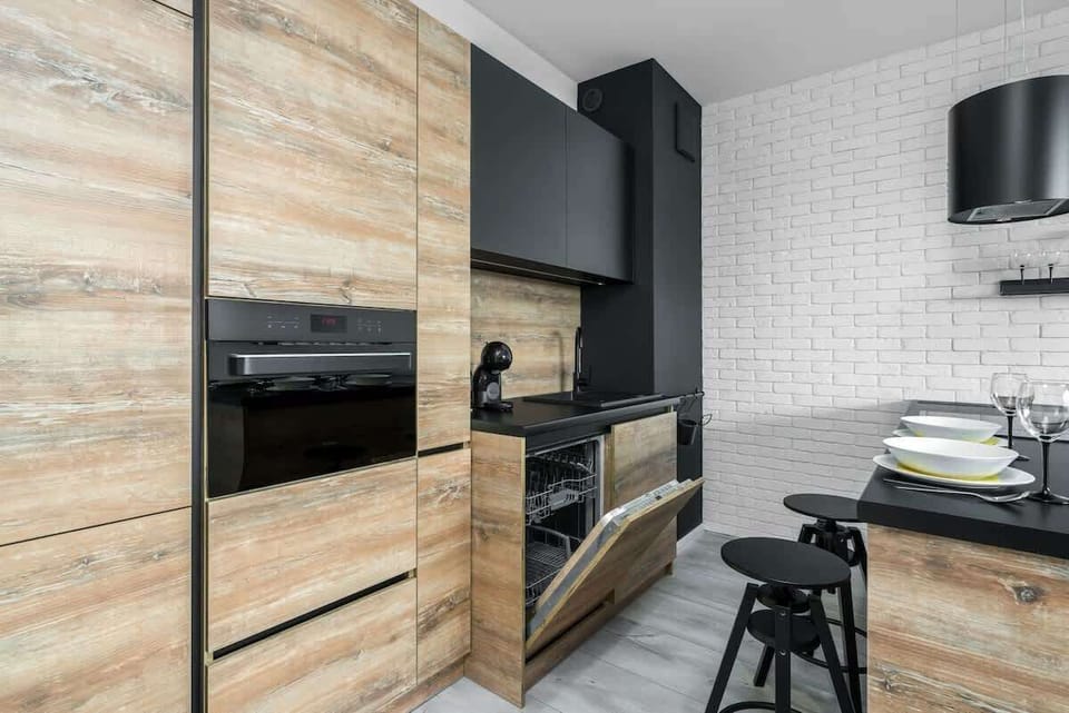 Another angle of the contemporary kitchen showcasing a functional layout with an integrated oven, ample counter space, and a decorative plant adding a touch of freshness.
