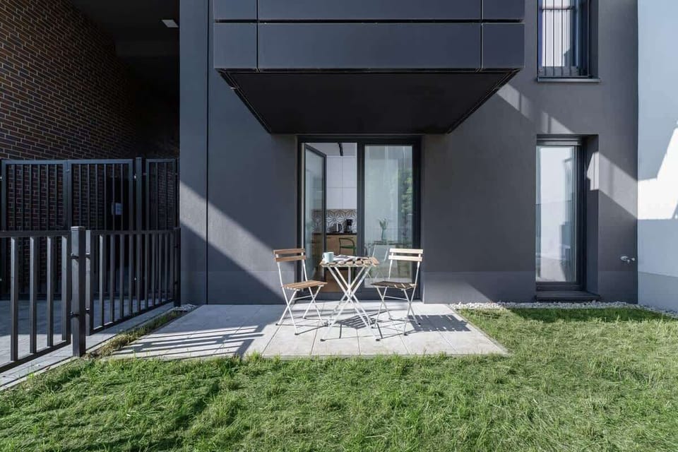 A private outdoor terrace with patio furniture, overlooking a grassy yard.