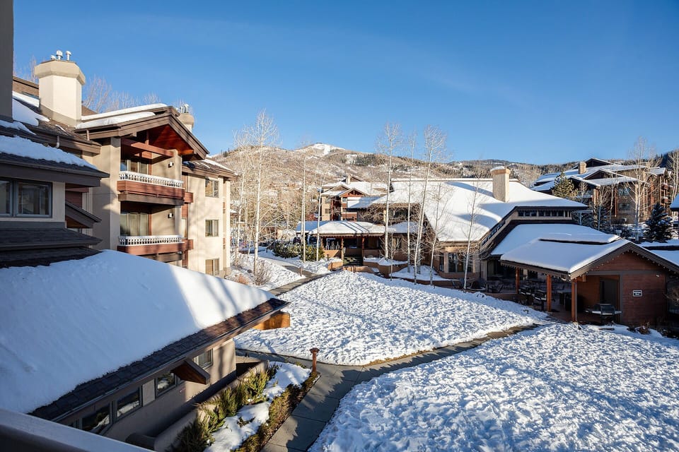 Snow-covered village nestled beneath mountain peaks creates a picturesque winter wonderland setting.