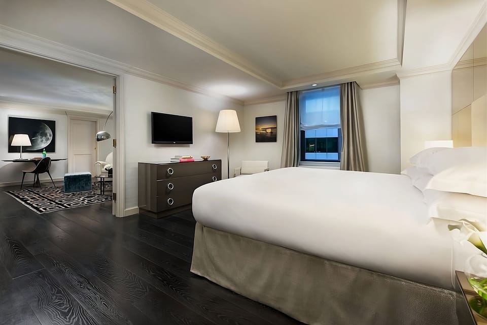 Unwind in a serene bedroom with plush bedding and city light.