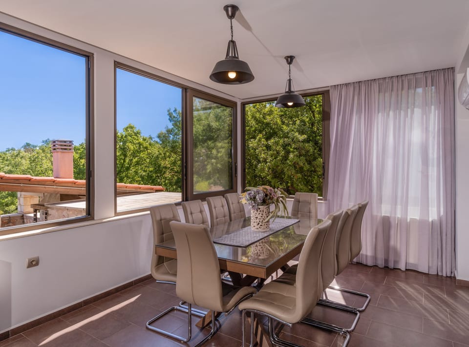 Indoor dining area with panoramic pool and garden view.
