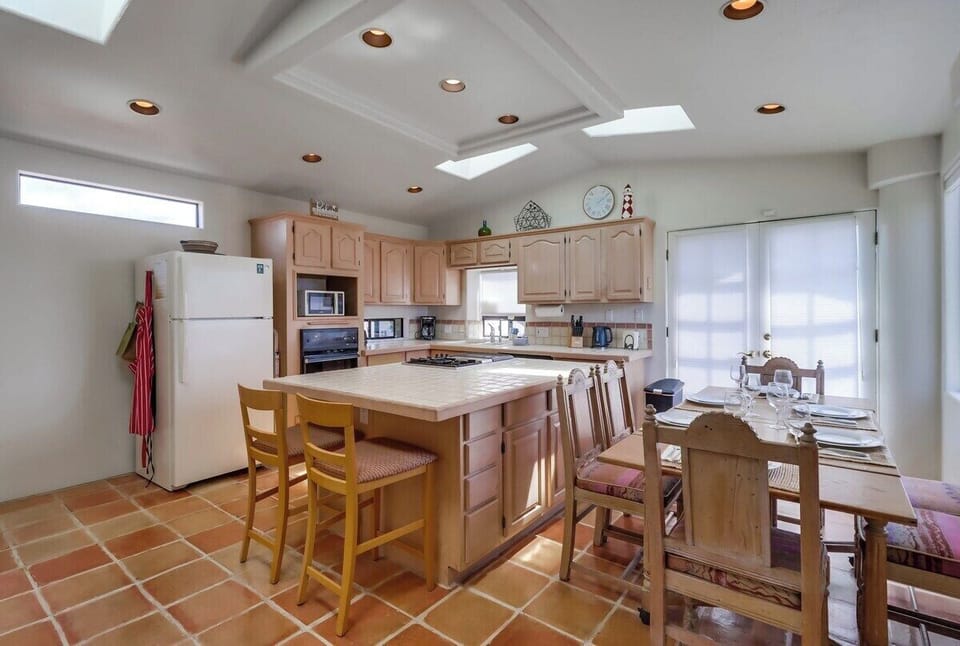 Kitchen with large island in the center, sliding glass doors to private patio, and seating for 4-6 guests. View of the ocean!