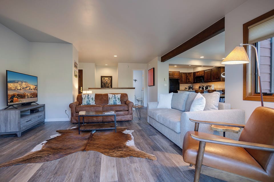 Settle into your cozy living space with plush seating, exposed wood beams, and a warm cowhide rug beneath your feet.