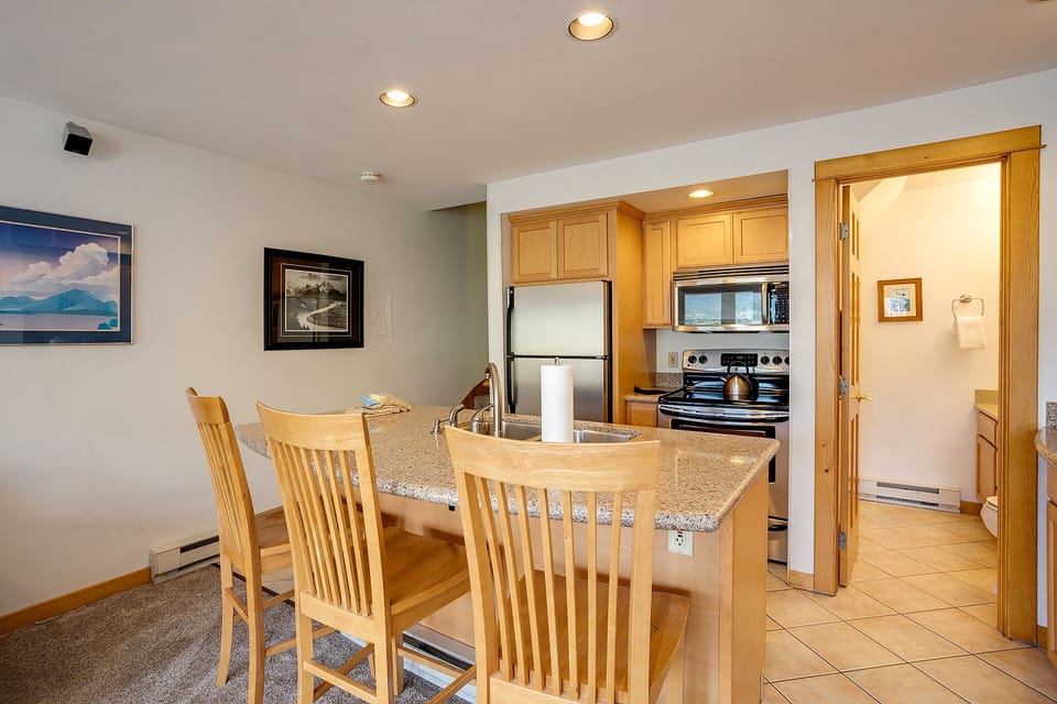 Your open kitchen features warm wood cabinetry and granite counters, perfect for preparing meals while chatting at the breakfast bar.