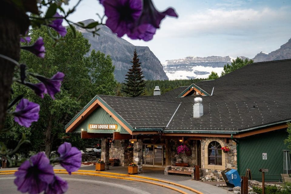 The inviting entrance awaits, framed by vibrant flowers and the majestic Rockies.