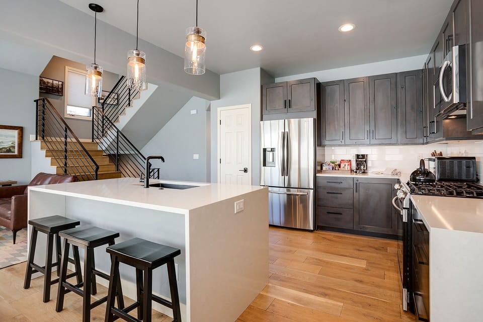 Your sleek modern kitchen awaits with stainless steel appliances, spacious island for morning coffee, and warm pendant lighting creating the perfect cooking atmosphere.