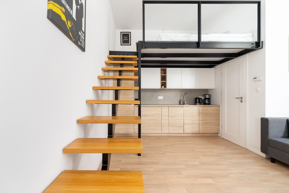 A perspective that focuses on the wooden staircase and a well-organized kitchenette in the background.