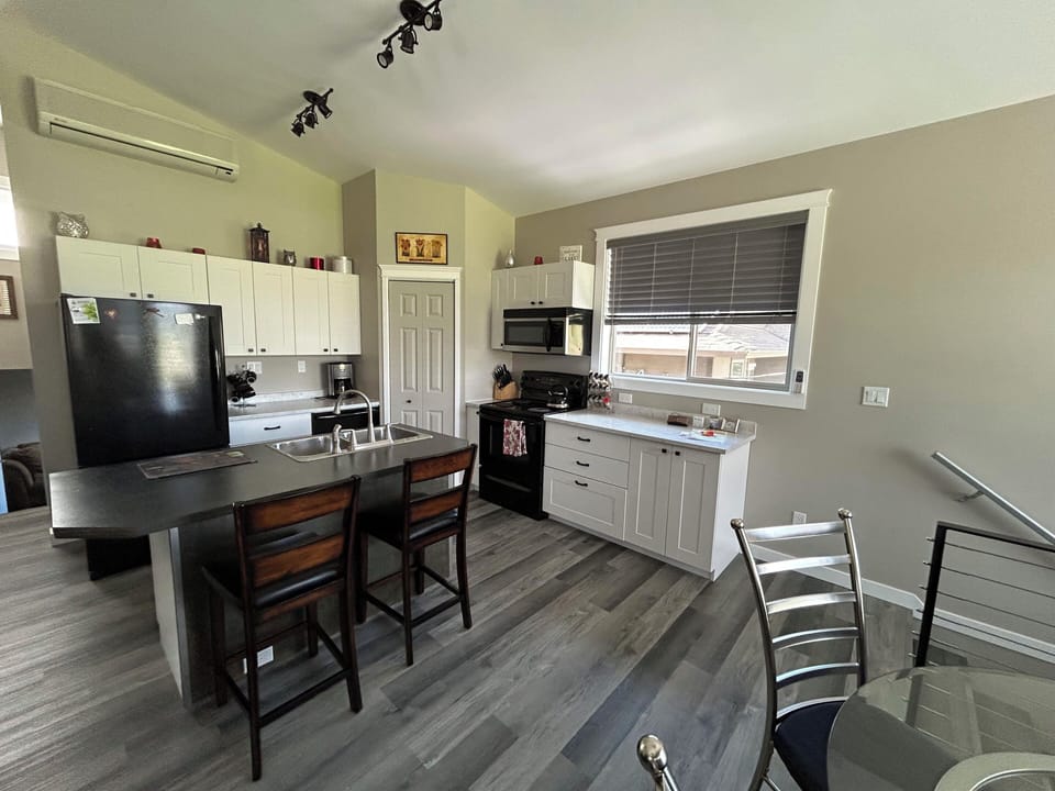 wider view of the kitchen with 2 dining options (bar seating and table)