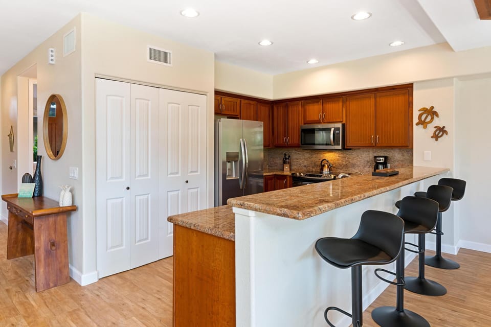 Fully equipped kitchen with granite counters, stainless steel appliances, and breakfast bar