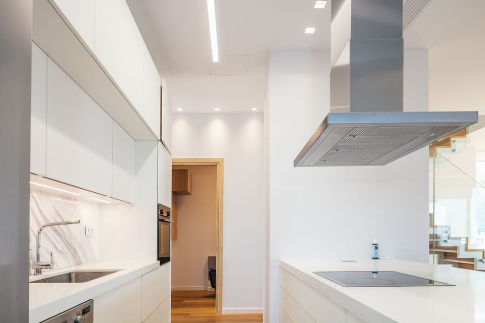The kitchen features sleek white surfaces, and wall-mounted appliances.