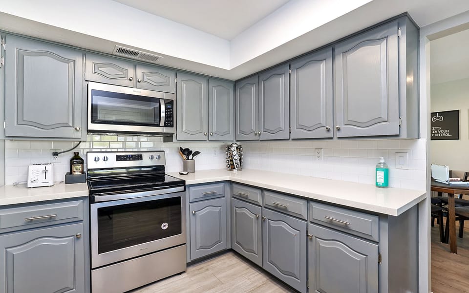 modern stainless steel appliances including: dishwasher, fridge, oven, microwave, stove top, coffee maker, pots and pans, and utensils.