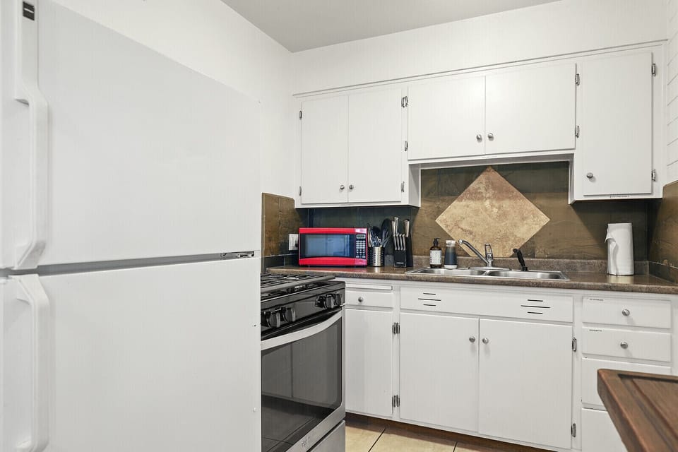 Kitchen includes dishwasher, fridge, stove top, coffee maker, toaster oven, pots and pans, plates, portable food containers, and utensils.
