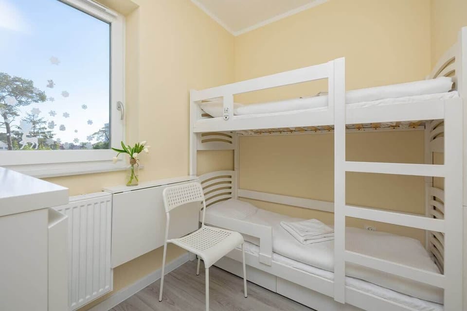 A compact bedroom featuring white bunk beds, perfect for accommodating children or additional guests.