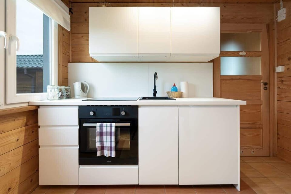 A modern kitchen corner featuring built-in appliances, white cabinets, and natural wooden finishes for a rustic-modern balance.