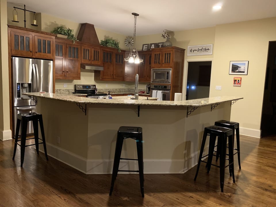 Large eat in kitchen with stainless steel appliances, island and four stools. 
