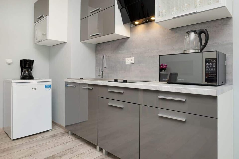 A modern kitchen area with built-in cabinets, stove, and small refrigerator.