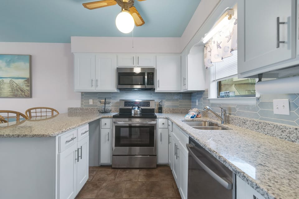 This gourmet kitchen, featuring stainless steel appliances and granite countertops, seamlessly flows into the spacious living area, perfect for entertaining.