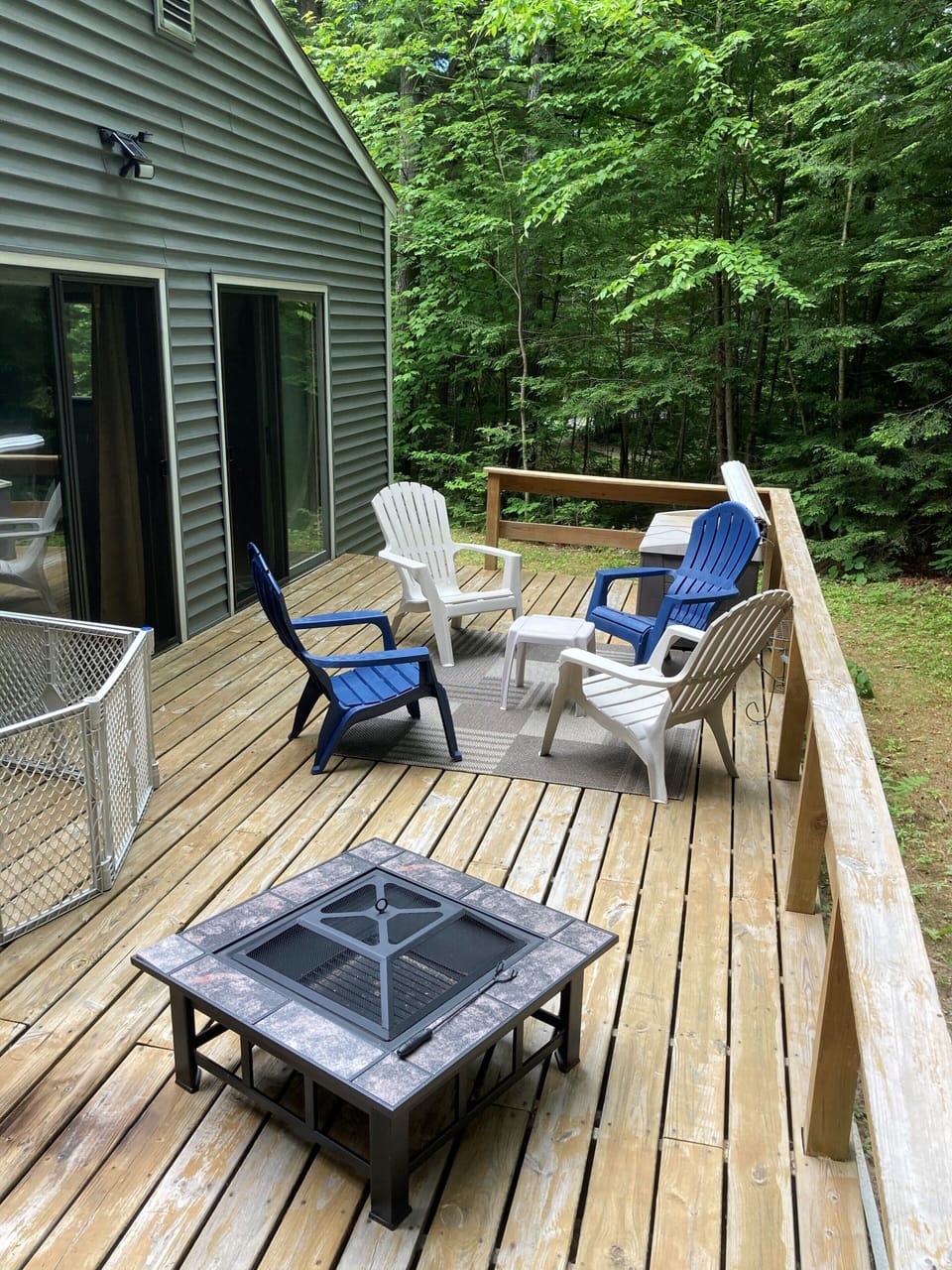 outdoor deck with fire pit and seating.  Surrounded by trees and small back yard