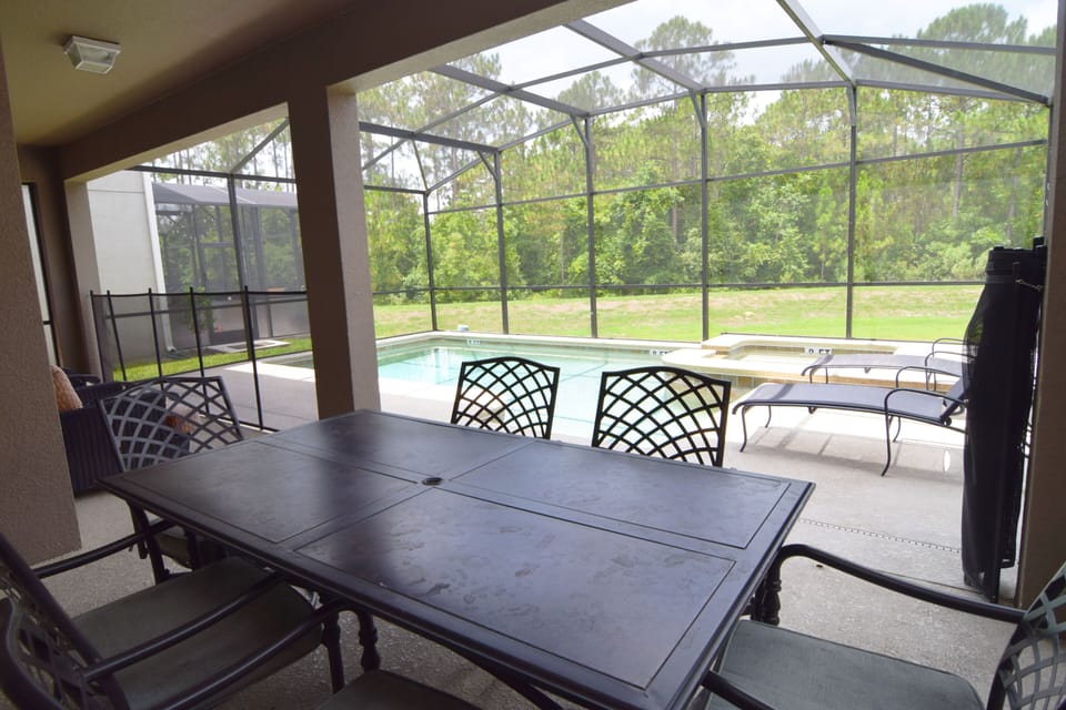 West-facing pool deck with four loungers, arm chairs and shaded dining area