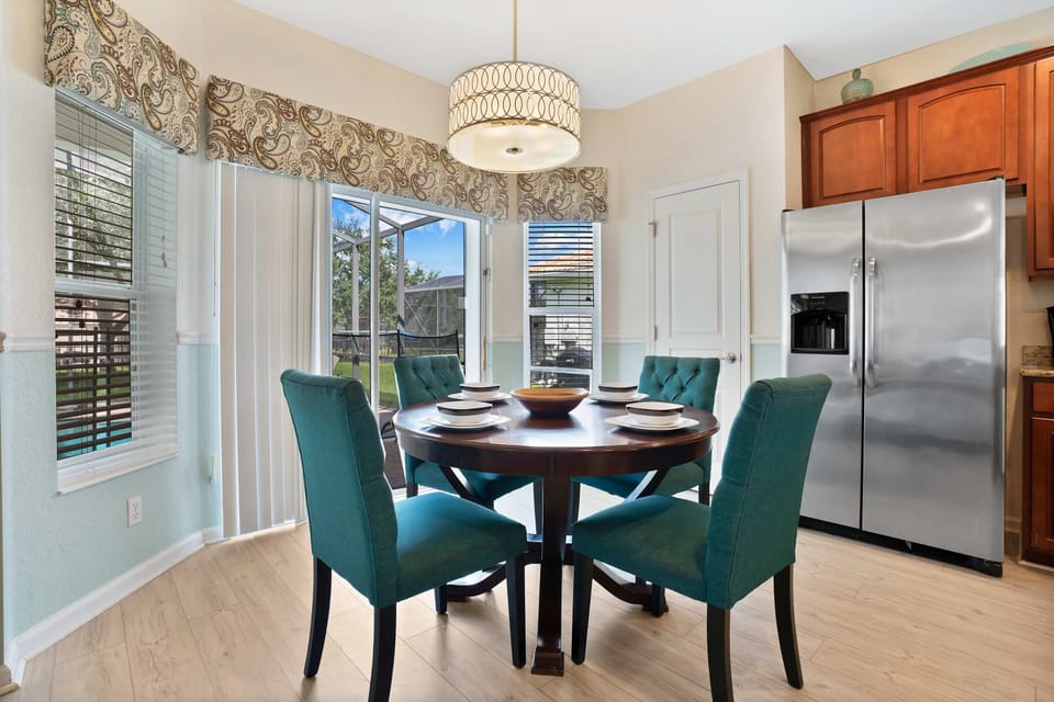 Charming breakfast nook with teal chairs, natural light, and views of the backyard.