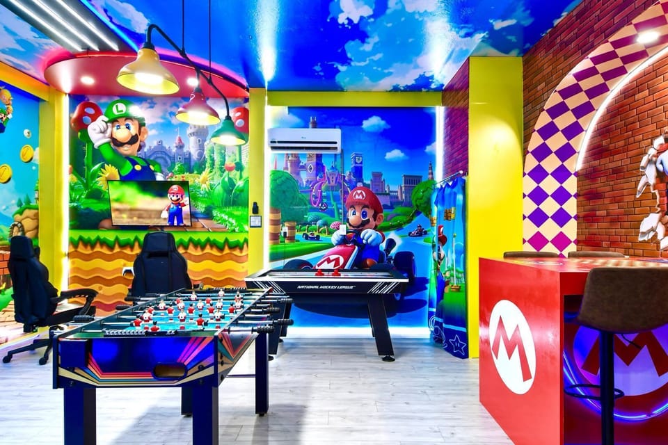 Vibrant Mario-themed game room with foosball, air hockey, arcade seating, and bold decor.