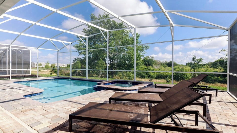 Screened-in pool and spa with sun loungers and serene nature views.