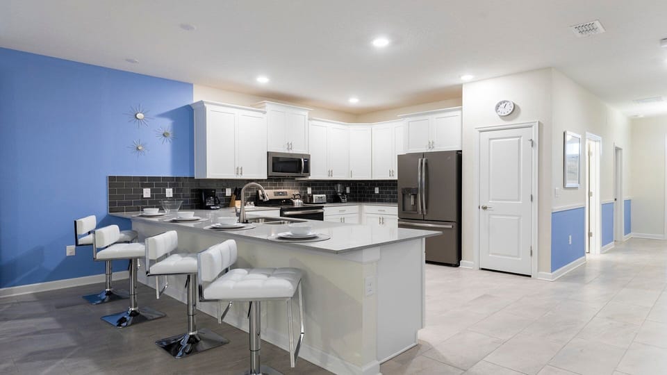 Modern kitchen with sleek island seating, stainless appliances, and bright decor.