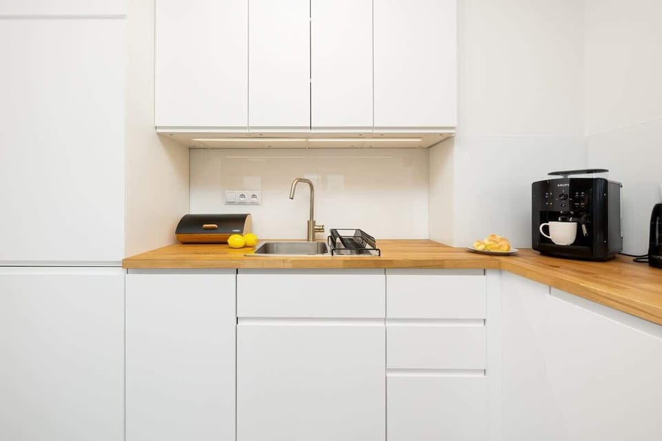 Zbliżenie na meble kuchenne i blat na którym stoi ekspres do kawy z biała filiżanką.