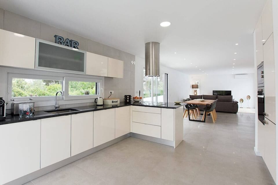 Modern open-plan kitchen with black countertops and cream cabinetry — Villa das Dunas, luxury holiday villa in Sesimbra
