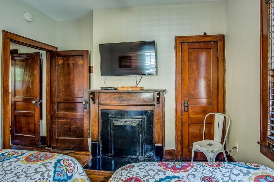 Guest bedroom with a faux fireplace, two full beds, and a smart TV.