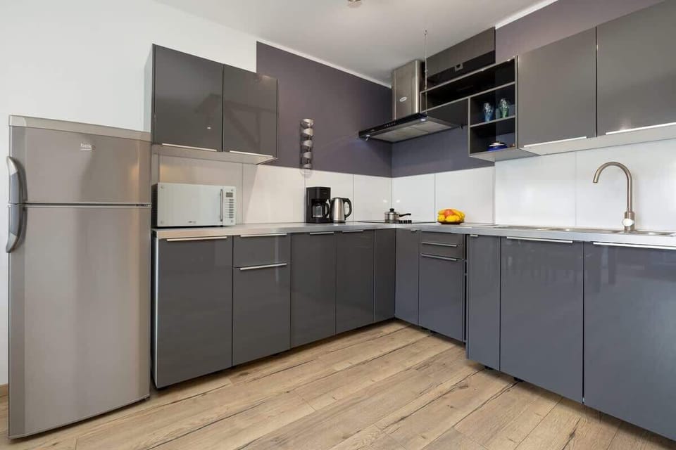 A well-equipped kitchen with modern gray cabinets, stainless steel appliances, and a wooden floor for a sleek finish.