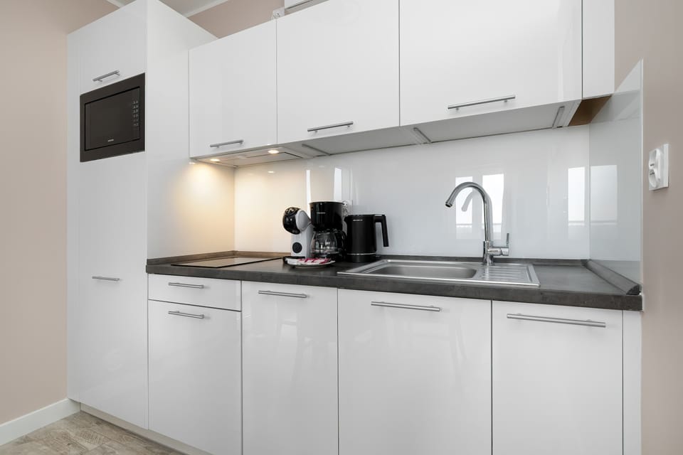 A compact white kitchen with modern cabinets, countertop appliances, and clean finishes.