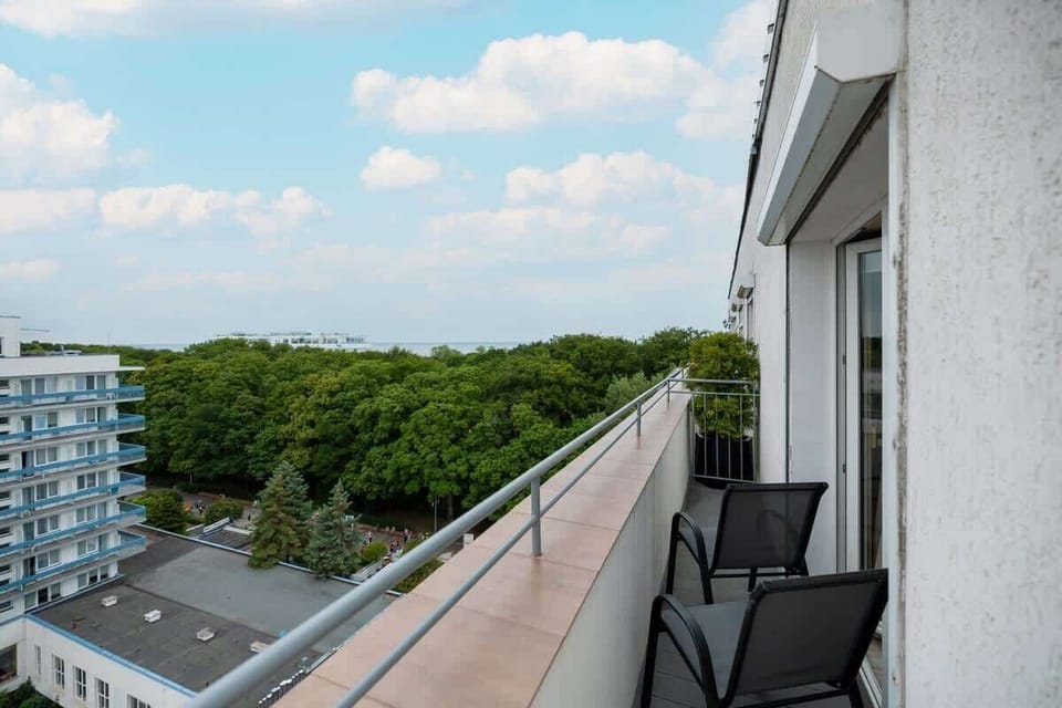 A view of the balcony with outdoor seating, offering a great place to relax while enjoying the surrounding greenery.