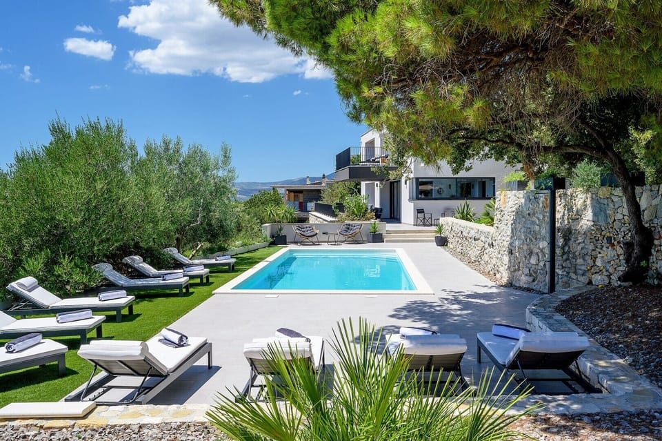 Pool area with deck chairs for relaxing on the sun of the vacation villa Yara in Kastela