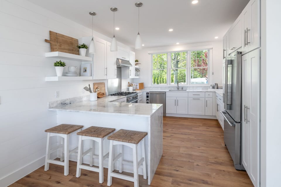 Dining towards Chef's kitchen and additional bar seating for 3