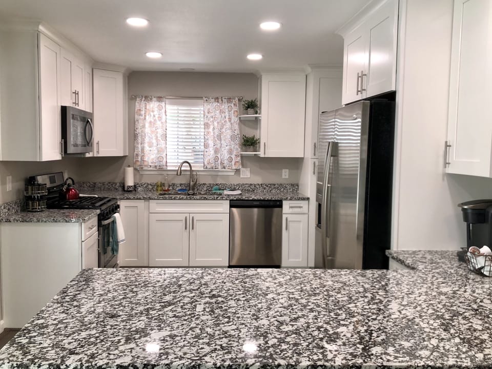 Kitchen with Stainless steel appliances, granite counters and bar that seats 4