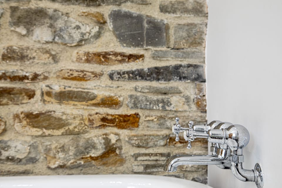 Traditional bath taps set against a rustic exposed stone wall â€“ cottage charm meets comfort