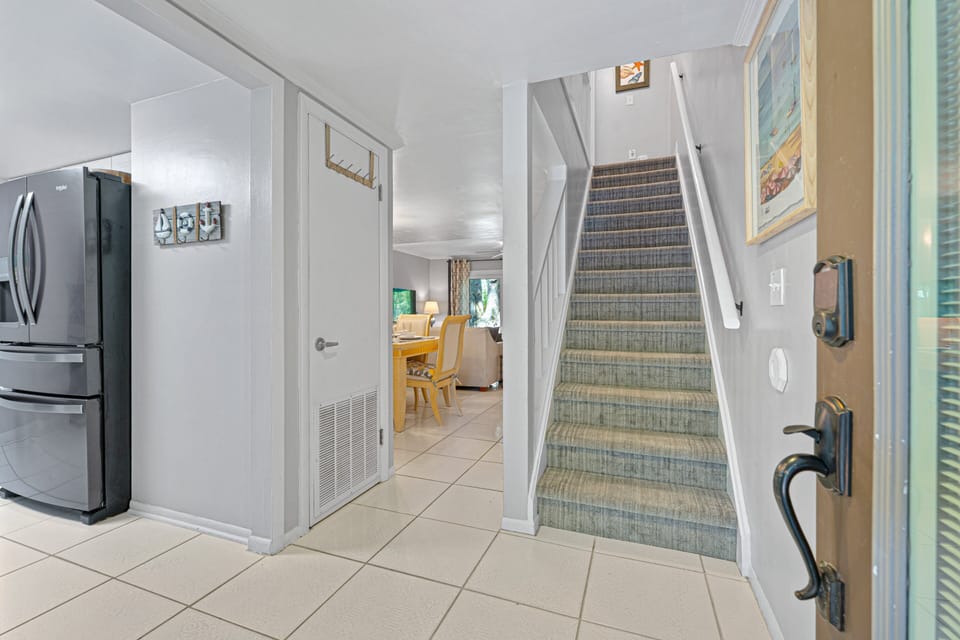 The tiled foyer leads seamlessly into the main living areas, while the carpeted staircase provides convenient access to the upper level.