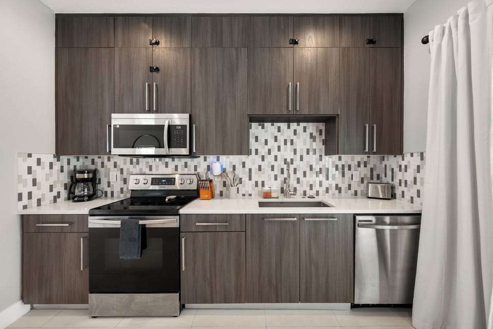 A clean kitchen setup with gray cabinets, mosaic tile, and everything you need
