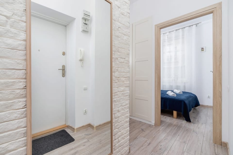 A corridor with a tall mirror on the wall and light wood flooring.
