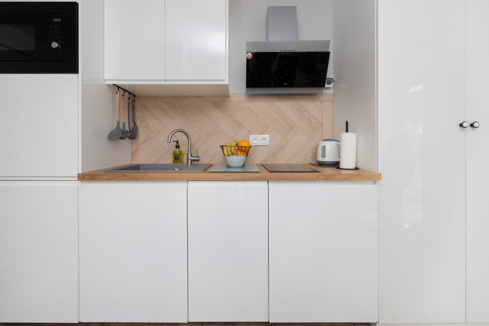 A sleek kitchen setup with white cabinetry, a wood-textured countertop, and built-in appliances.